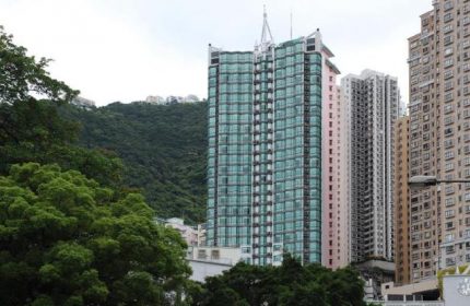 Bishop Lei International House: Gay-friendly hotel view. High-rise building with green glass facade, surrounded by other buildings and lush greenery.