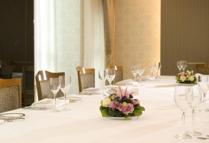Bishop Lei International House dining. Table setting with flowers, wine glasses, and white tablecloth. Gay-friendly hotel in Hong Kong.