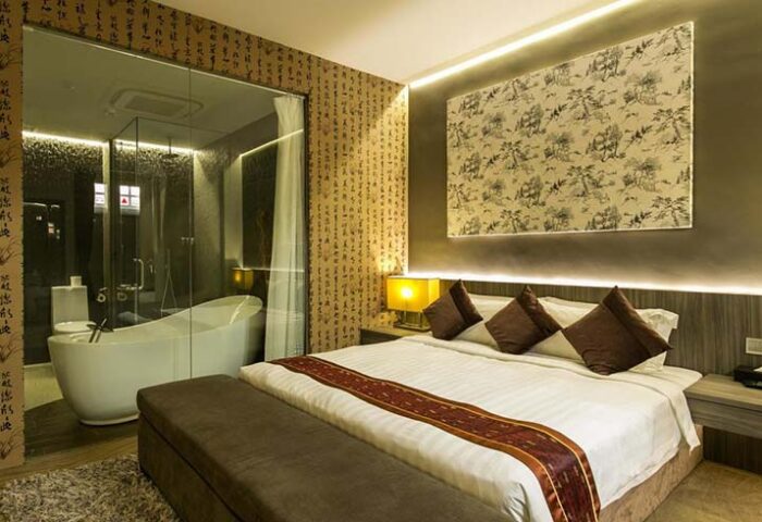 Bliss Hotel Singapore room. Gay-friendly hotel with a bedroom featuring a king-size bed and a bathroom with a modern bathtub. Asian-inspired decor.