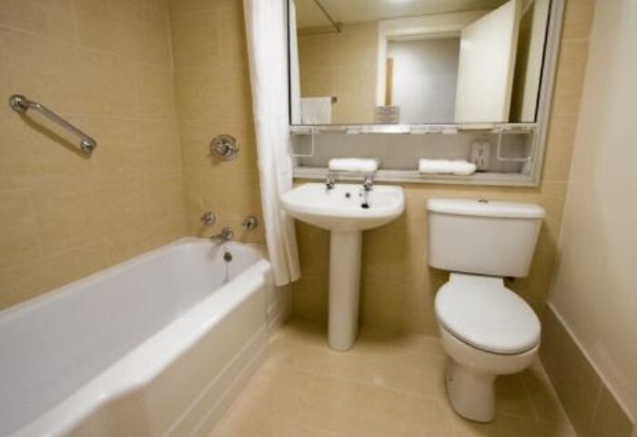 Blooms Hotel gay-friendly bathroom. Bathtub, sink, and toilet in a clean, well-lit space. Ideal for gay men's travel, ensuring comfort and convenience.
