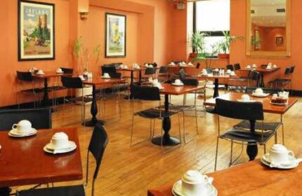 Blooms Hotel's dining area, a gay-friendly hotel. Tables with teacups fill the room. A mirror and art adorn the walls in this Dublin hotel.
