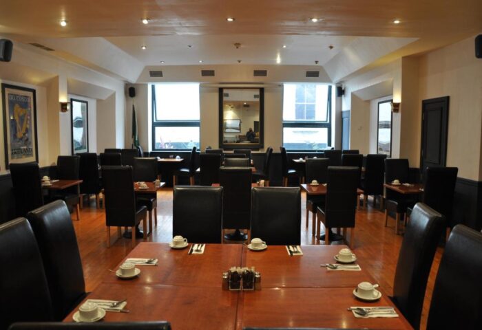 Blooms Hotel's dining room. Gay-friendly hotel with set tables, black chairs, and wooden floors. Ideal for gay men travel in a welcoming space.