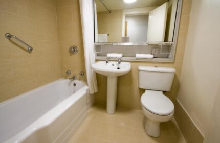Blooms Hotel bathroom. Gay-friendly hotel featuring a clean, well-lit bathroom with a bathtub, toilet, and sink. Ideal for gay men travel.