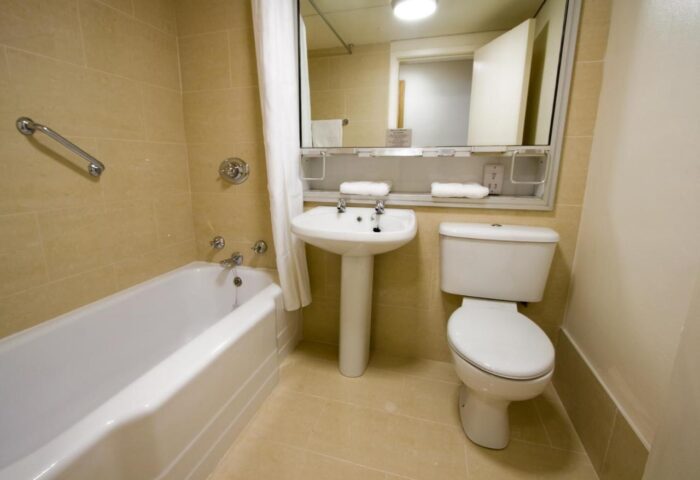 Blooms Hotel bathroom. Gay-friendly hotel featuring a clean, well-lit bathroom with a bathtub, toilet, and sink. Ideal for gay men travel.