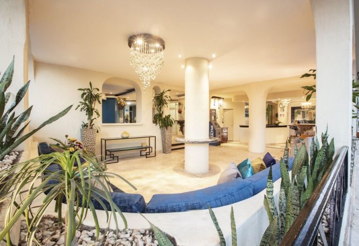Lobby at Blue Chairs Resort by the Sea, a gay-friendly, adults-only hotel. Blue couch, chandelier, plants. Gay travel in Puerto Vallarta.