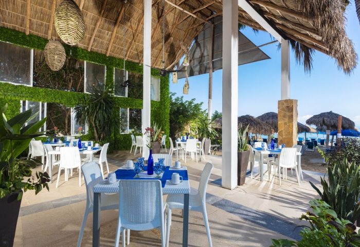 Blue Chairs Resort by the Sea adults-only gay-friendly hotel restaurant. Tables with blue decor, beach view, and thatched roof.