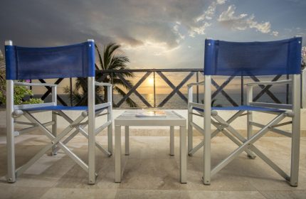 Blue Chairs Resort by the Sea, adults only gay-friendly hotel. Beach view from balcony with blue chairs and table at sunset.