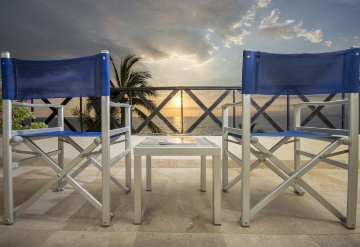 Blue Chairs Resort by the Sea, adults only gay-friendly hotel. Beach view from balcony with blue chairs and table at sunset.