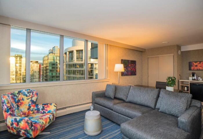Blue Horizon Hotel suite with city view. Gay-friendly hotel room with sofa, chair, and skyline. Modern interior design for gay men's travel.