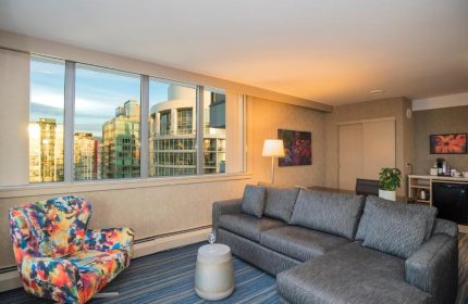 Blue Horizon Hotel suite with city view. Gay-friendly hotel room with sofa, chair, and skyline. Modern interior design for gay men's travel.