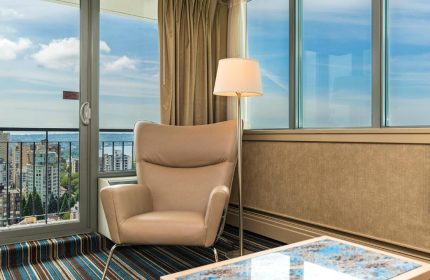 Room at gay-friendly Blue Horizon Hotel. Armchair, lamp, and city view. Gay travel lodging. LGBTQ+ hotel. Gay men's vacation.