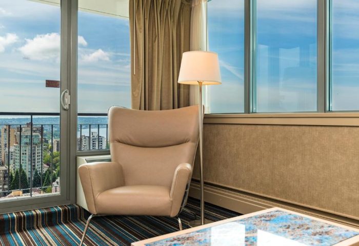 Room at gay-friendly Blue Horizon Hotel. Armchair, lamp, and city view. Gay travel lodging. LGBTQ+ hotel. Gay men's vacation.
