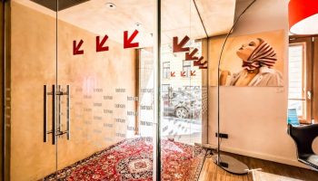 Bohem Art Hotel entrance. Glass doors with Bohem text, red arrows, and a patterned rug. Gay-friendly hotel interior with artwork.