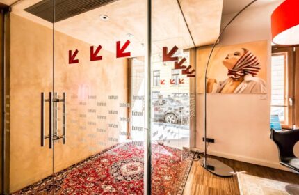 Bohem Art Hotel entrance. Glass doors with Bohem text, red arrows, and a patterned rug. Gay-friendly hotel interior with artwork.