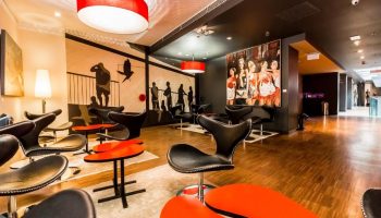 Bohem Art Hotel lobby's seating area. Modern design with black chairs, red tables, and artistic wall decor. Gay-friendly hotel interior.