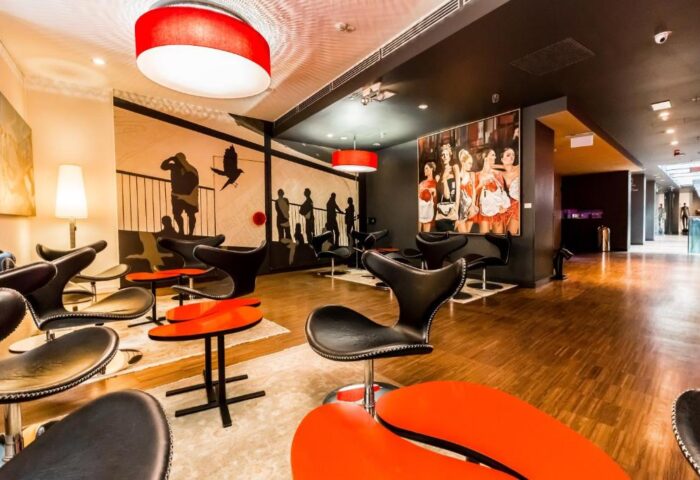 Bohem Art Hotel lobby's seating area. Modern design with black chairs, red tables, and artistic wall decor. Gay-friendly hotel interior.