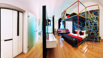 Bohem Art Hotel room. Gay-friendly hotel with a unique design, featuring a bed with colorful geometric frame and a modern interior.