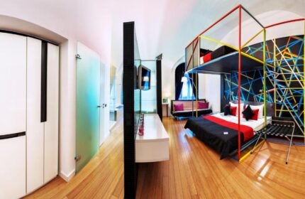 Bohem Art Hotel room. Gay-friendly hotel with a unique design, featuring a bed with colorful geometric frame and a modern interior.