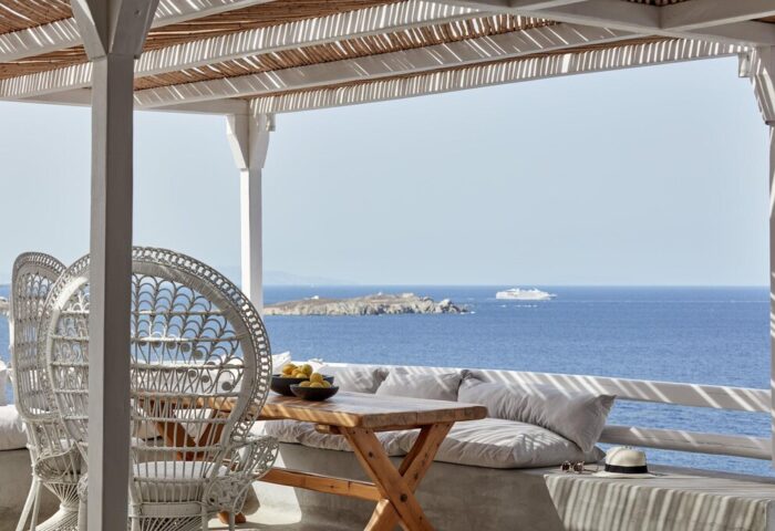 Boheme Mykonos Hotel adults-only terrace view. Wicker chairs, table with lemons, and ocean vista. Gay-friendly hotel for luxury travel.