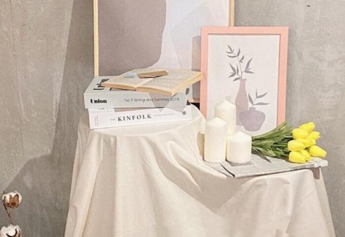Book Tea Bed SHINJUKU-GYOEN hotel still life. Books, candles, tulips, and framed art on a draped table. Gay-friendly hotel decor.