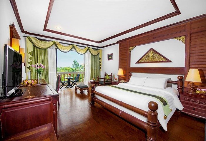 Borei Angkor Resort & Spa gay-friendly hotel room. Wood floors, balcony, king bed, desk, TV, and seating area. Luxury travel for gay men.