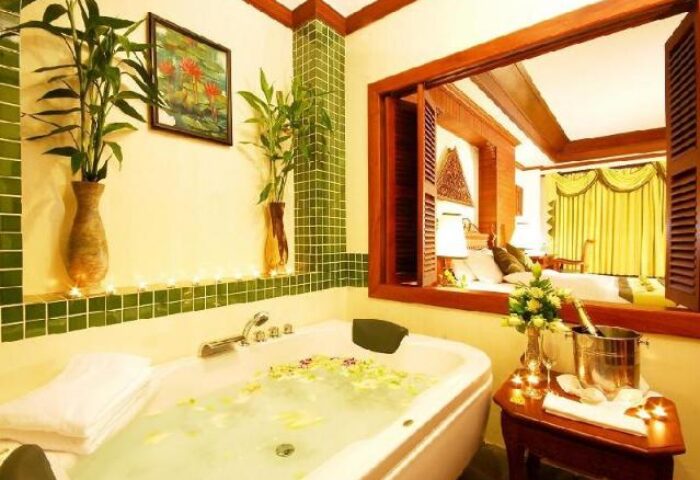 Gay-friendly Borei Angkor Resort & Spa: Luxurious bathroom with tub, champagne, and view to bedroom. Ideal for gay travel, relaxation.