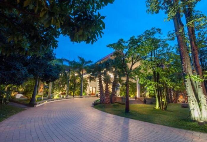 Borei Angkor Resort & Spa entrance at night. Gay-friendly hotel with lush greenery and a welcoming driveway. Luxury travel destination.