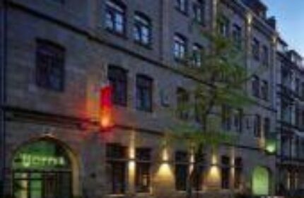 Exterior of Boutique Hotel 026 Koln St. Michael, a gay-friendly hotel in Cologne, Germany. Facade view at dusk, lights illuminating the entrance.