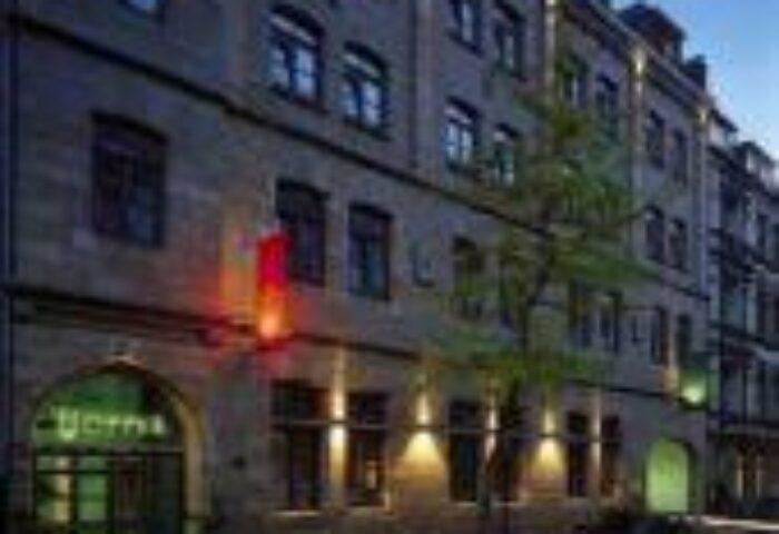 Exterior of Boutique Hotel 026 Koln St. Michael, a gay-friendly hotel in Cologne, Germany. Facade view at dusk, lights illuminating the entrance.