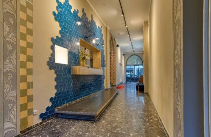 Boutique Hotel 026 Köln St. Michael lobby. Gay-friendly hotel with blue honeycomb tile wall, reception desk, and patterned floor. Stylish design.