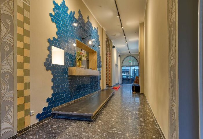 Boutique Hotel 026 Köln St. Michael lobby. Gay-friendly hotel with blue honeycomb tile wall, reception desk, and patterned floor. Stylish design.