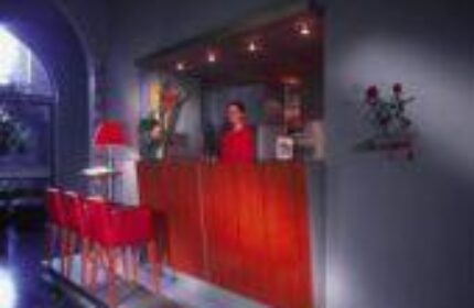 Reception area at Boutique Hotel 026 Koln St. Michael, a gay-friendly hotel. Red desk and chairs. Travel advice for gay men in Cologne.