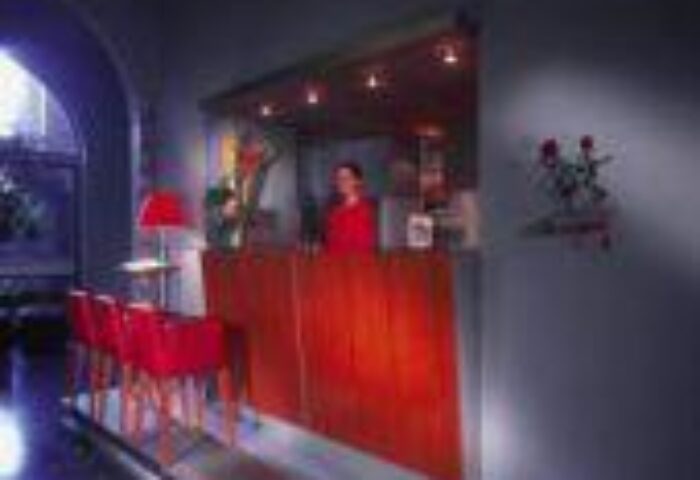 Reception area at Boutique Hotel 026 Koln St. Michael, a gay-friendly hotel. Red desk and chairs. Travel advice for gay men in Cologne.