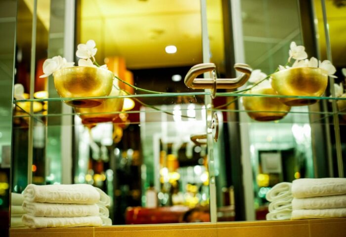 Das Tyrol Boutiquehotel's stylish bathroom. Gold bowls with white flowers sit above stacked towels. A gay-friendly hotel detail.