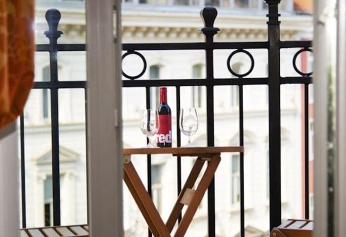 Gay-Friendly Boutiquehotel Das Tyrol balcony view. Wine bottle and glasses on a small table. Ideal for gay men's travel in Vienna.