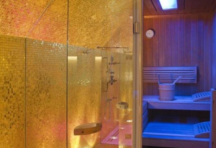 Gay-friendly Boutiquehotel Das Tyrol sauna and shower. Upscale hotel for gay men's travel with golden mosaic tiles and wood sauna.