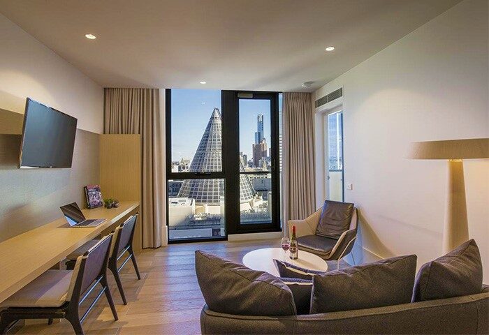 Gay-Friendly Brady Hotels Central Melbourne room with city view. Modern interior, desk, TV, and seating area. Ideal for gay men travelers.