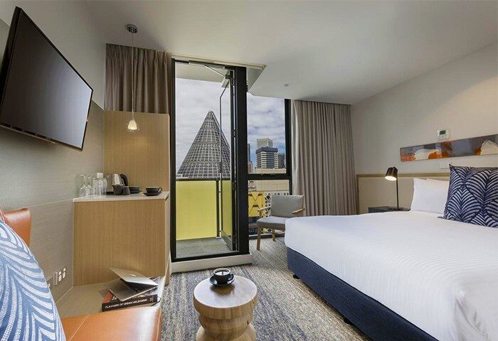 Brady Hotels Central Melbourne room. Gay-friendly hotel with a bed, balcony, and city views. Modern design, ideal for gay men's travel.