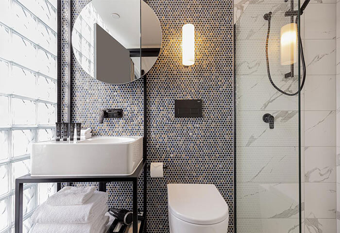 Brady Hotels Jones Lane gay-friendly hotel bathroom. Features a modern sink, shower, toilet, and stylish tilework. Ideal for gay travel.