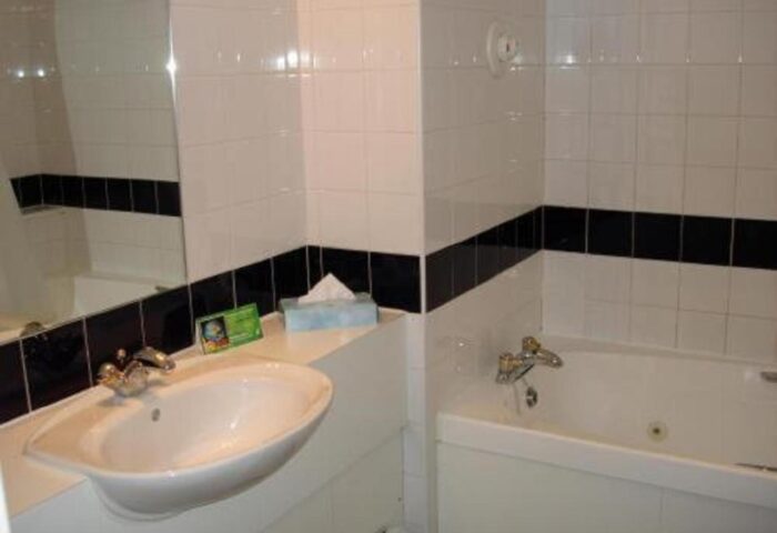 Bathroom at gay-friendly Britannia Manchester Hotel. White tiles, sink, bathtub. A comfortable stay for gay travelers in Manchester.