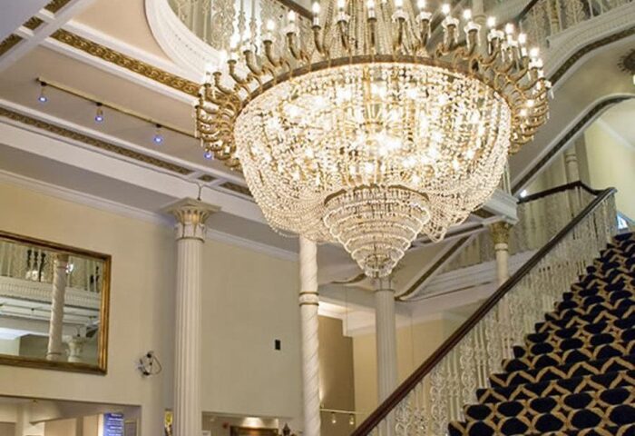 Britannia Manchester Hotel's grand interior. Ornate chandelier, staircase, and columns. Gay-friendly hotel with luxurious design elements.