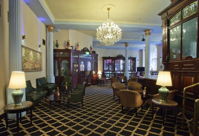 Britannia Manchester Hotel's interior. Elegant lobby with chandelier, columns, and seating areas. Gay-friendly hotel perfect for travel.