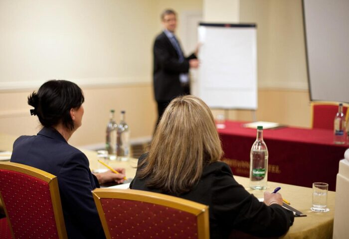 Britannia Manchester Hotel conference room. Attendees at a business meeting, the speaker is pointing at a whiteboard. Gay-friendly hotel.