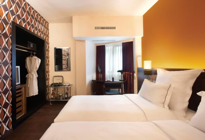 Brown Acropol Hotel room. Gay-friendly hotel with twin beds, retro decor, geometric wallpaper, and a minibar. Stylish accommodation for gay travelers.