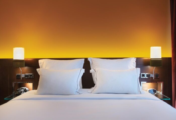 Brown Acropol Hotel bedroom. Gay-friendly hotel room with white linens, pillows, bedside lamps, and a warm, inviting ambiance. Brown Hotels member.