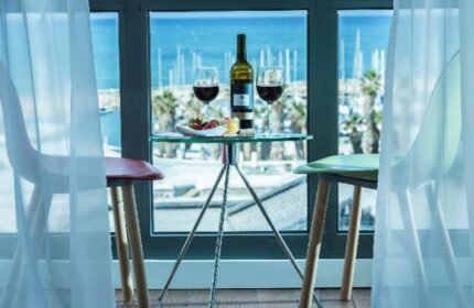 Brown Seaside Hotel view. Wine and fruit on a glass table, with a sea view. Gay-friendly hotel room, perfect for a romantic getaway.