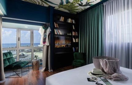 Brown Seaside Hotel room. Gay-friendly hotel with seaside view, bookshelf, tropical ceiling, and stylish decor. Ideal for gay travel.