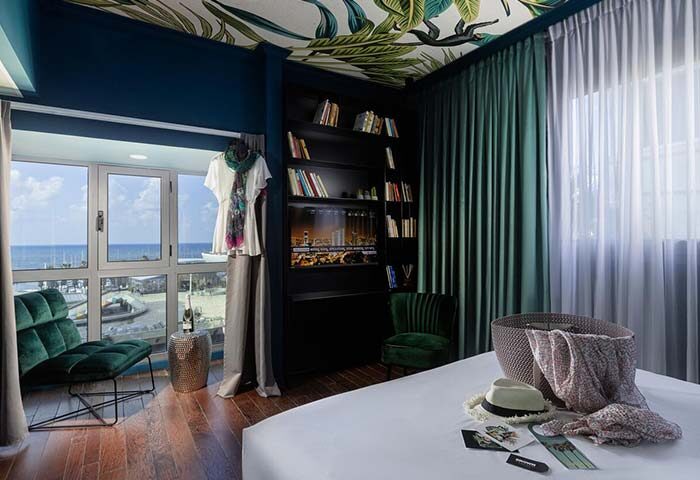 Brown Seaside Hotel room. Gay-friendly hotel with seaside view, bookshelf, tropical ceiling, and stylish decor. Ideal for gay travel.