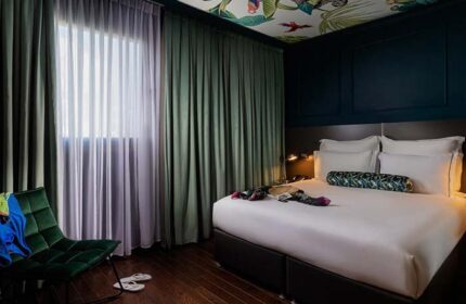 Brown Seaside Hotel bedroom interior. Gay-friendly hotel room with a bed, chair, curtains, and tropical-themed ceiling. Member of Brown Hotels.