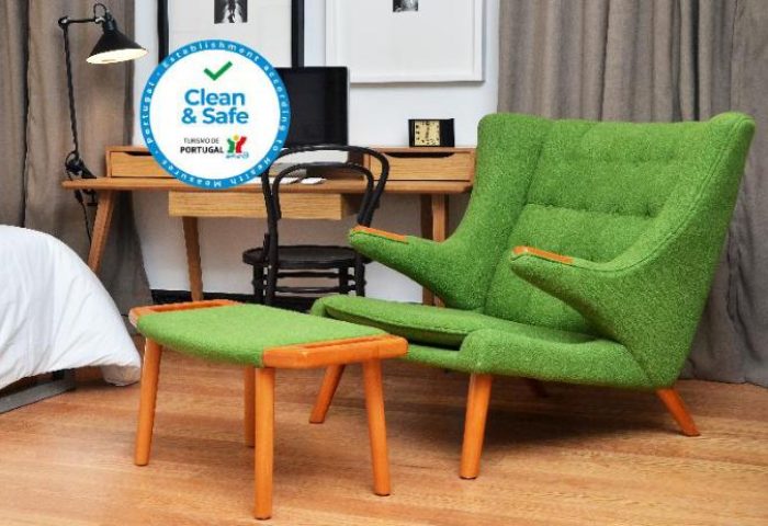 Browns Boutique Hotel, gay-friendly hotel room. Green armchair and footstool. Desk with lamp and TV. Clean & Safe Portugal seal.